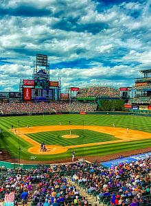 A vibrant baseball stadium on a sunny day, with a game in progress and a crowd filling the stands.