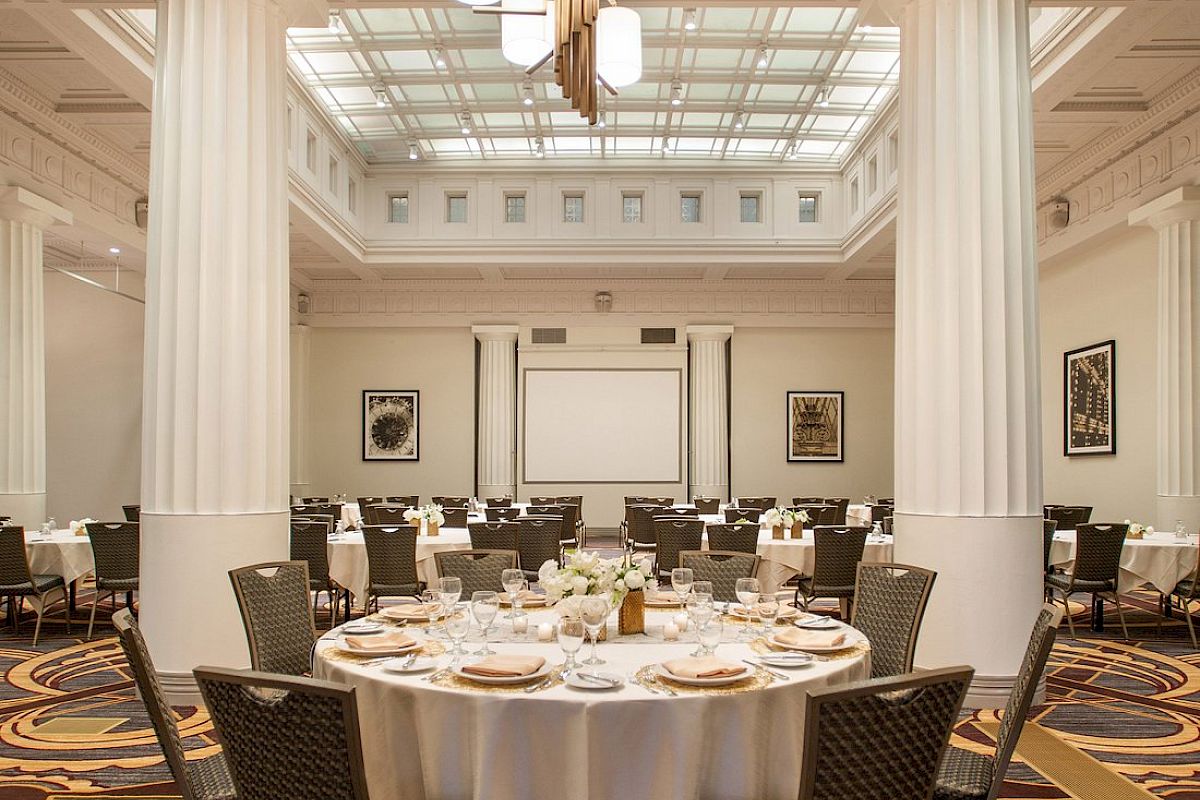 A banquet hall with a round table set for an event, featuring elegant decor and a chandelier.