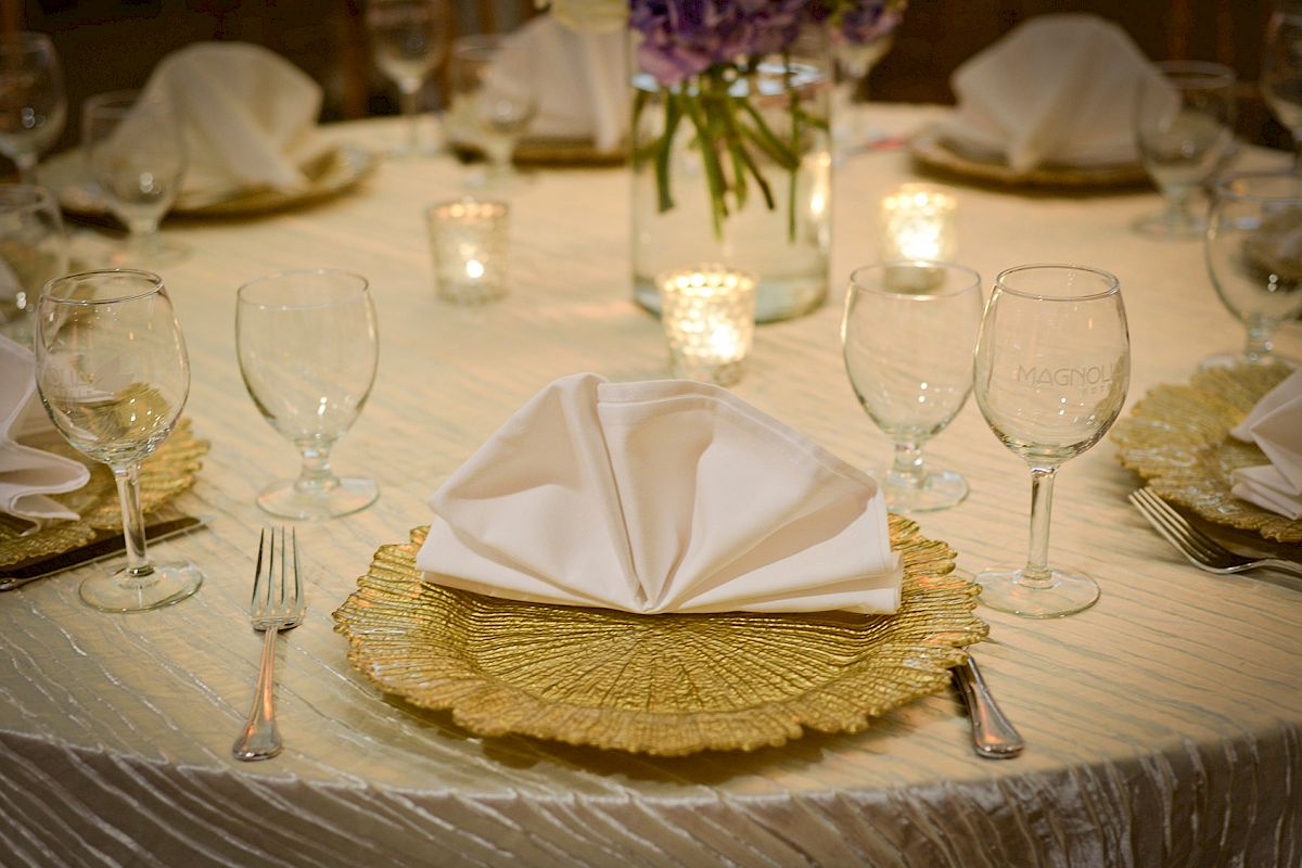 A table set for a formal occasion with elegant tableware, folded napkins, and candles, creating a sophisticated ambiance.