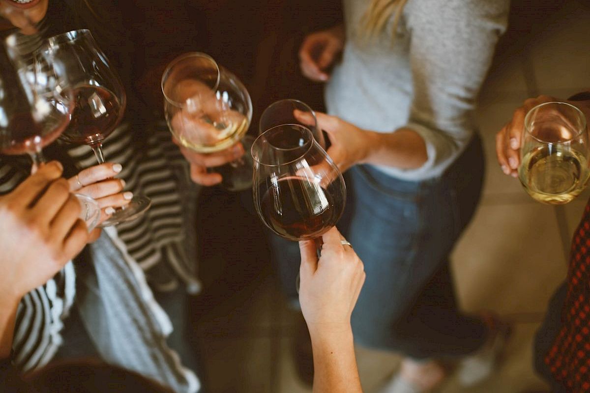 People holding and clinking wine glasses in a casual social gathering.