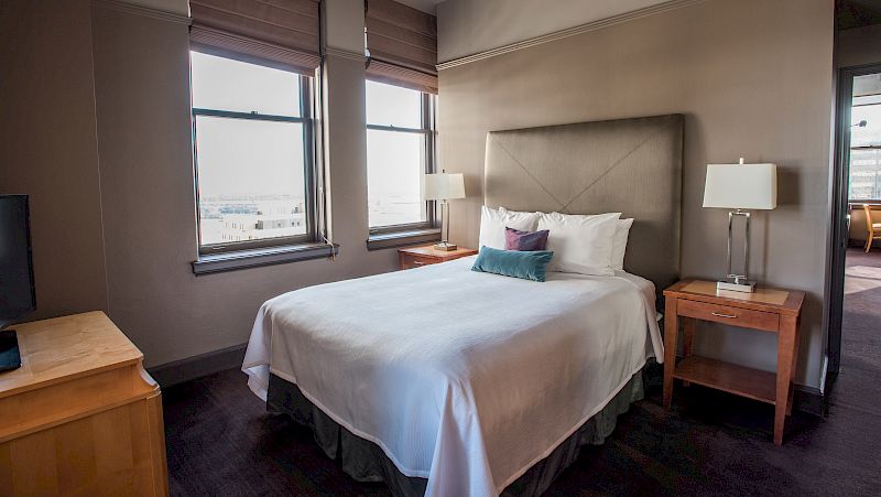 A hotel room with a bed, nightstands, and a window.