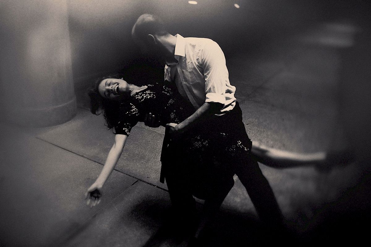 A man dips a woman in a dramatic dance pose on a dimly lit street.