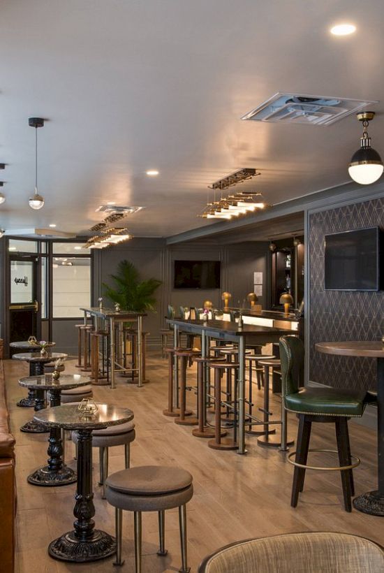 The image shows a stylish bar with high stools, tables, dim lighting, and decorative walls. There's a cozy seating area and an elevator.