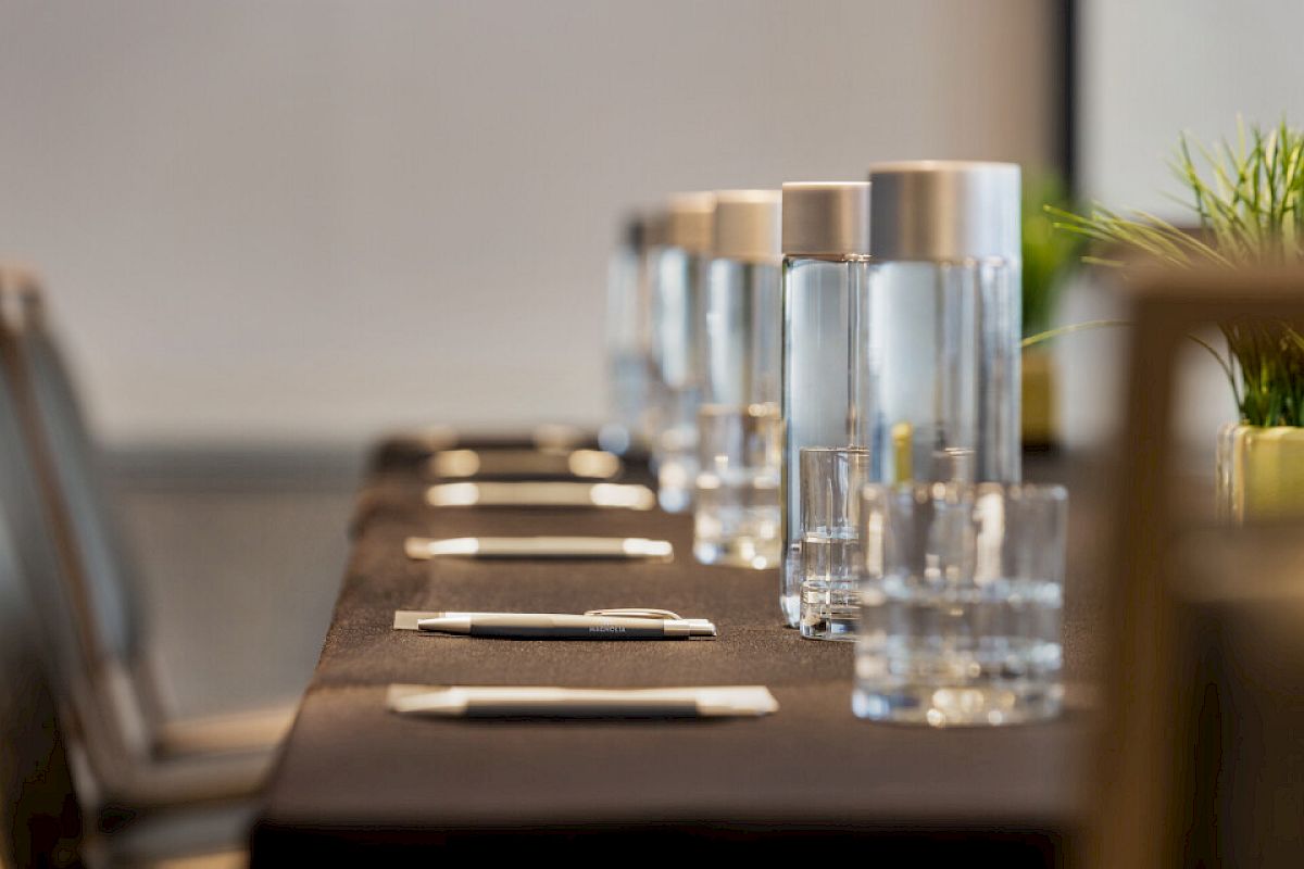 A conference table set with notebooks, pens, and water bottles, ready for a meeting.