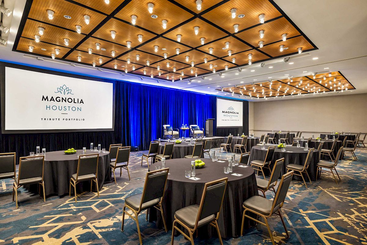 A conference room with round tables, chairs, and large screens displaying 