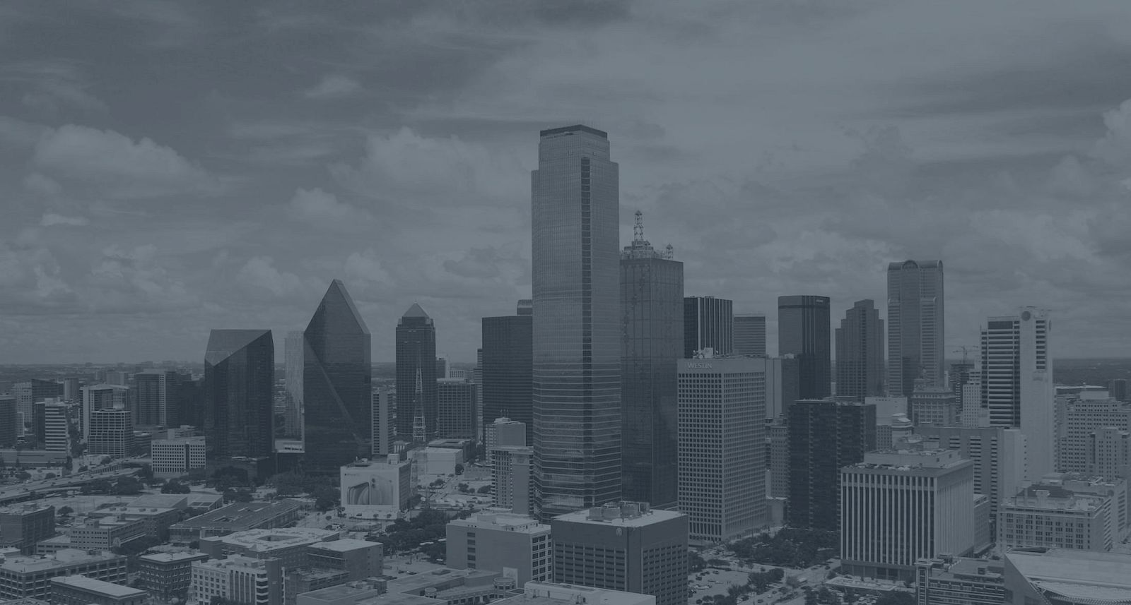 A city skyline with tall buildings under a cloudy sky.