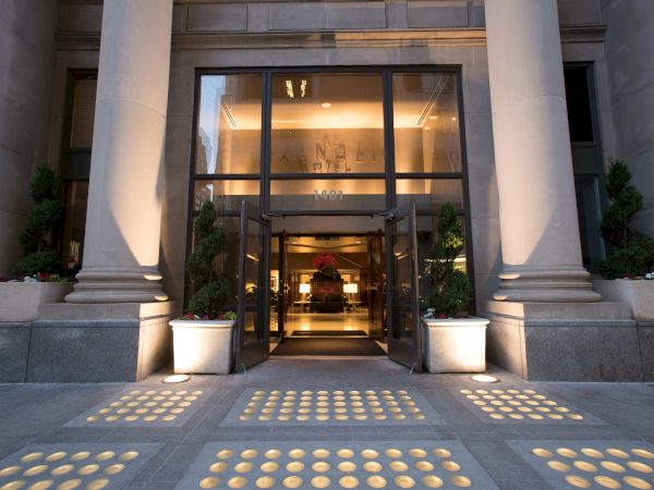 A grand entrance with tall columns, glass doors, and potted plants leads into a beautifully lit interior space.