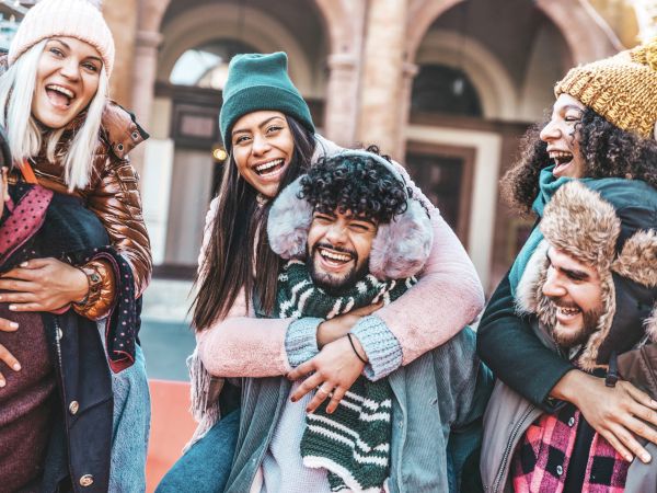 A group of friends in winter clothes, smiling and having fun outdoors.