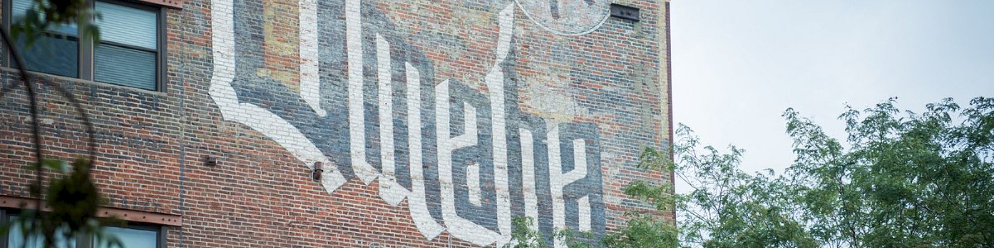 A brick wall features a painted design with the word 