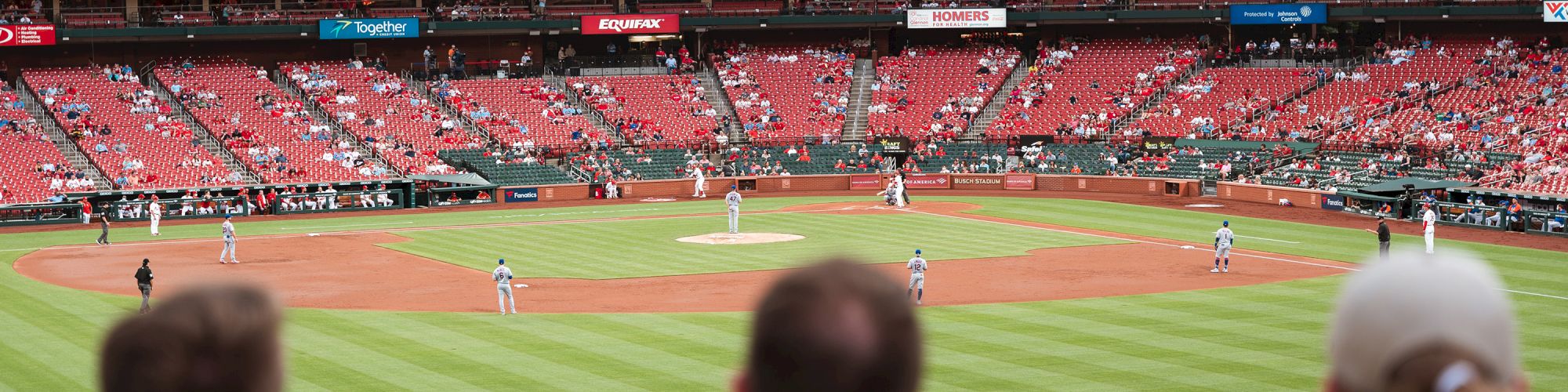 The image shows a baseball game in progress from the perspective of spectators, with players on the field and fans in the stands.
