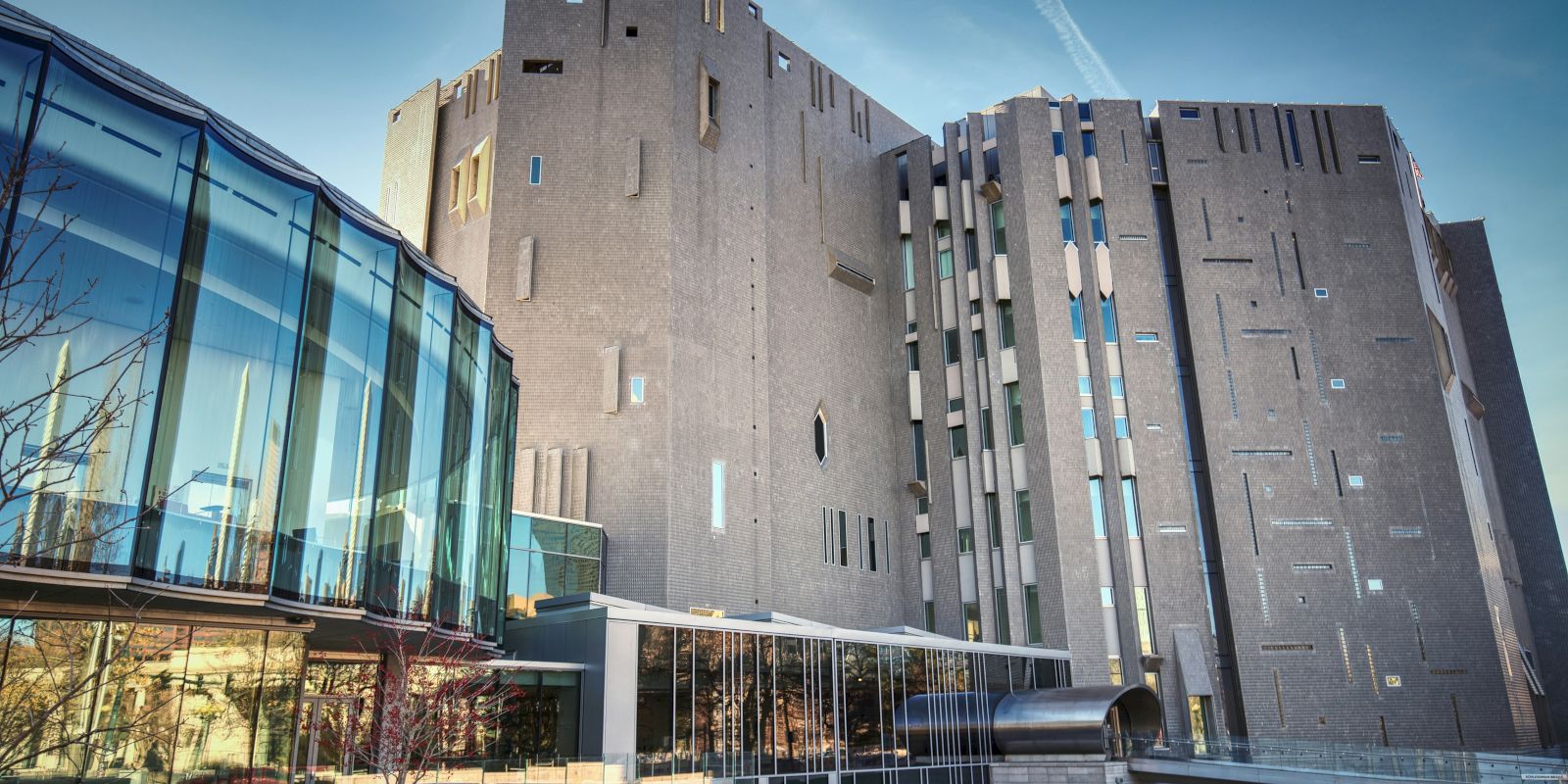 This image shows a modern building with a unique facade and large glass windows, featuring both angular and curved architectural elements.