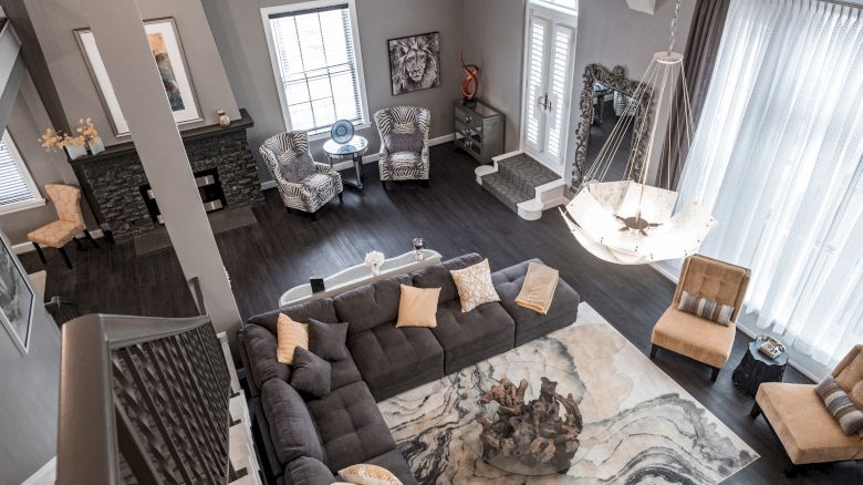 An elegant living room with a large sectional sofa, armchairs, chandelier, and marble-patterned rug.