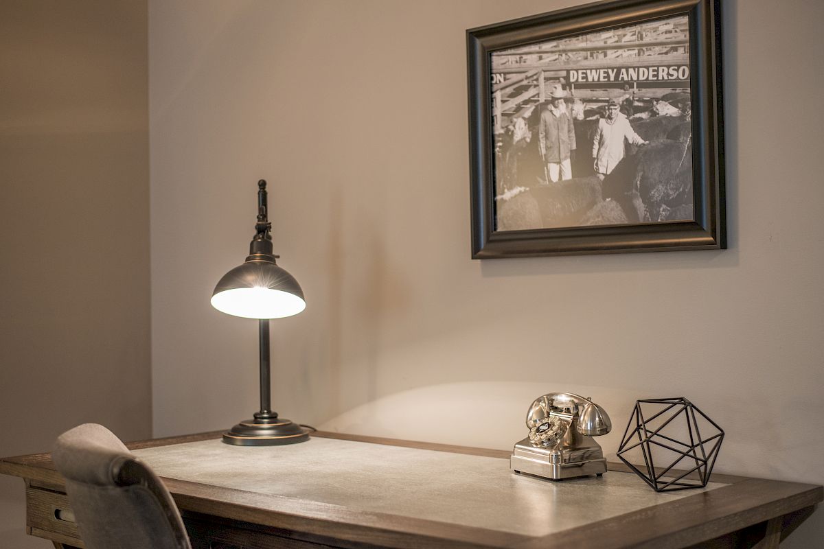 A desk with a vintage phone, geometric decor, and a lamp. A framed photo labeled