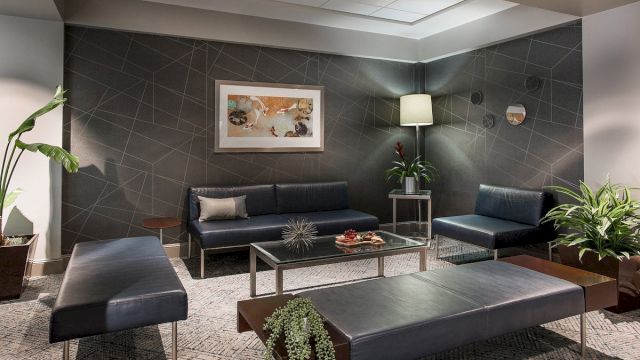 A modern lobby seating area with leather furniture, glass tables, and plants.