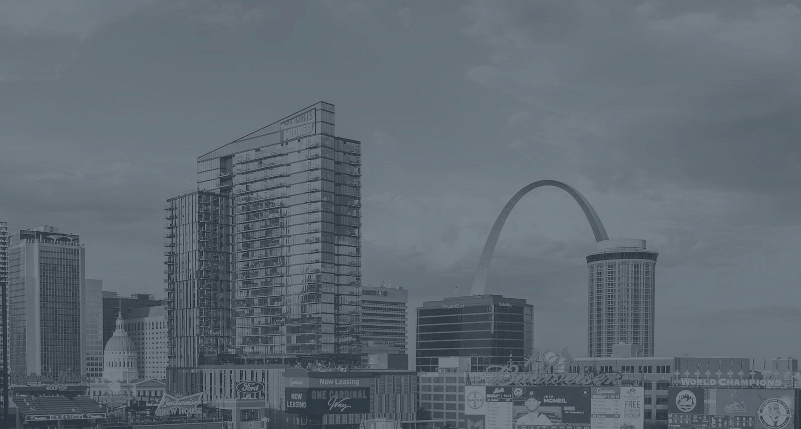 The image shows a city skyline with modern buildings, a prominent arch, and clear skies.