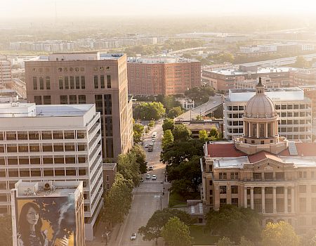 The image shows an aerial view of a cityscape with buildings and a street, including a domed structure amidst modern architecture in the scene.